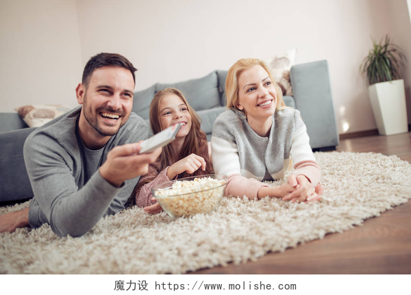 躺在地毯上看电视的一家人4.他们在家里闲呆着，笑着和家人一起看电视.